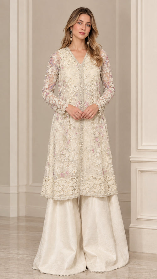 Front view of woman wearing cream embroidered floral lace kurti with wide flared trousers