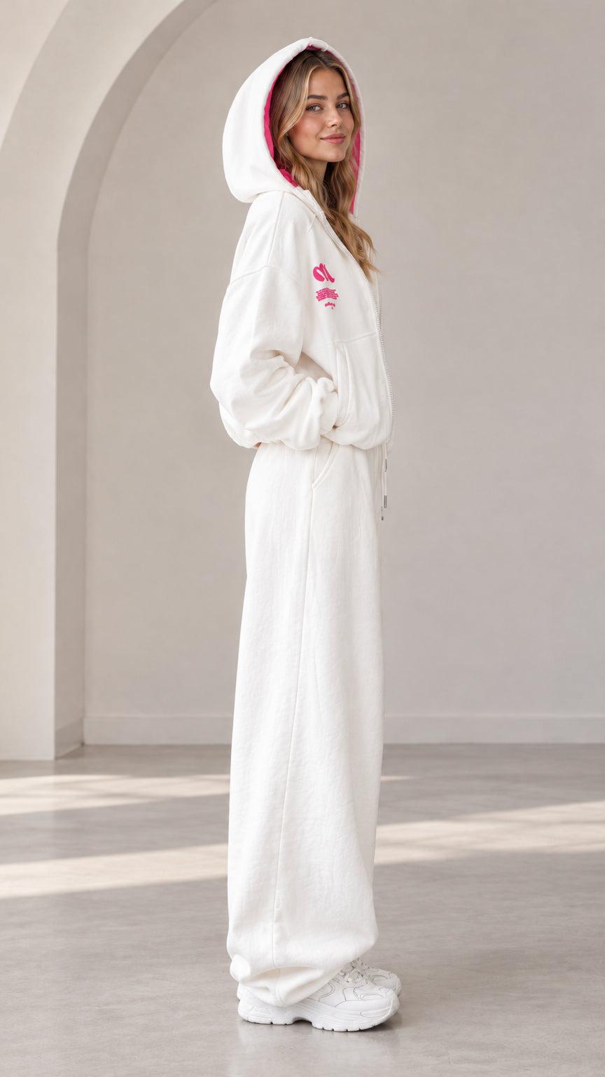 Side view of model wearing off-white wide-leg sweatpants and zip hoodie set