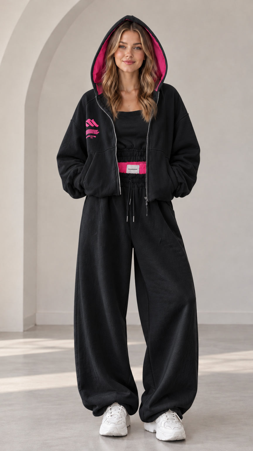 Model wearing black two-piece tracksuit set with contrast hot pink lined hood
