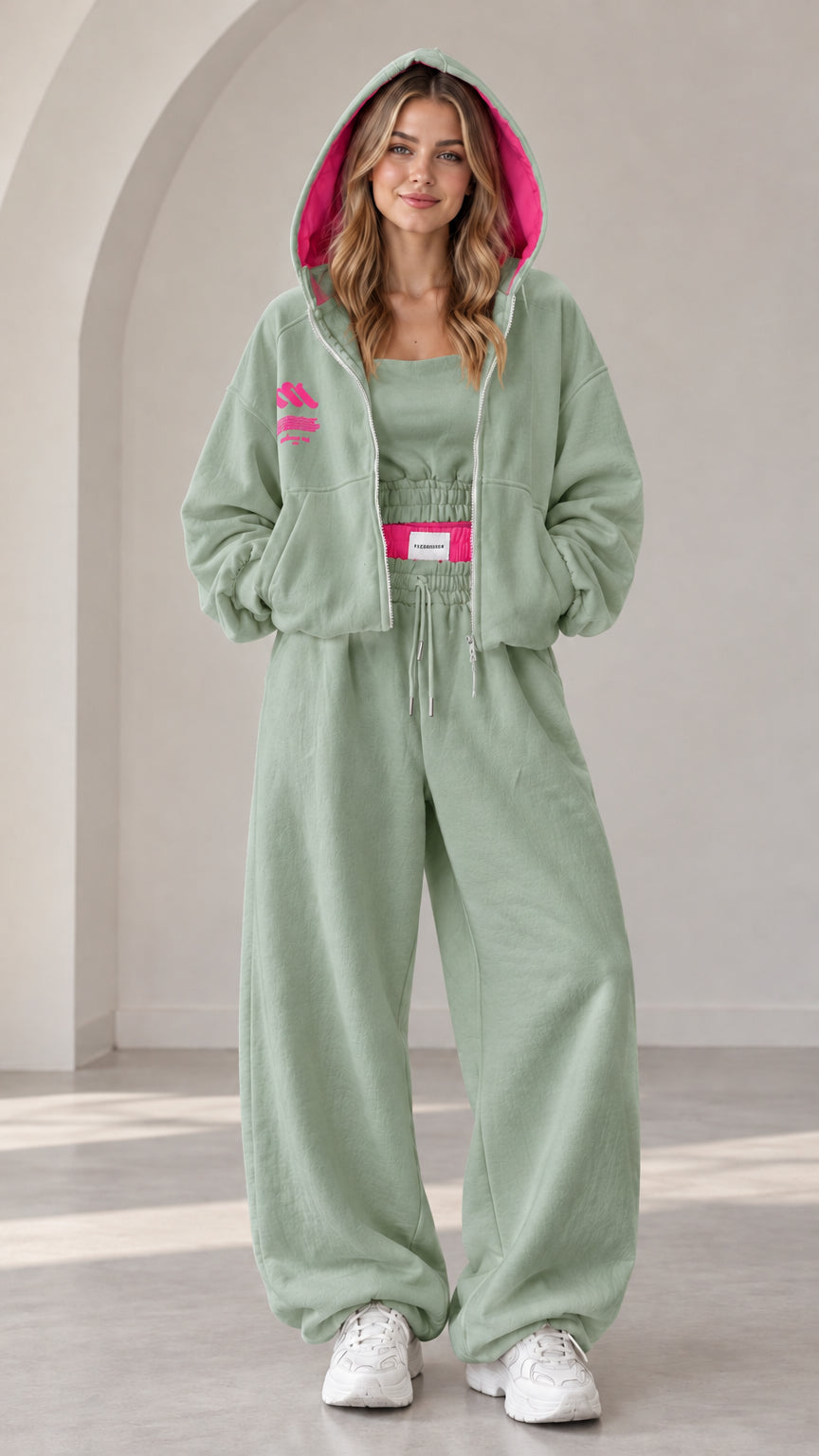 Model wearing sage green two-piece tracksuit set with contrast hot pink lined hood